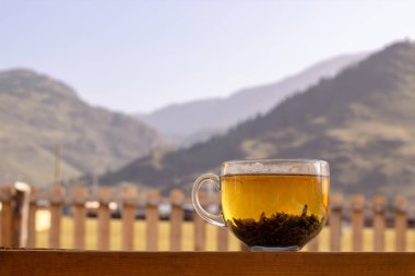 Dağların arkasında cam bardak yeşil çay.