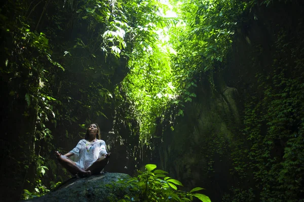 Jovem bela mulher asiática praticando Yoga posando sentado em posição de lótus meditando sobre uma pedra em uma paisagem natural deslumbrante cheia de vegetação — Fotografia de Stock