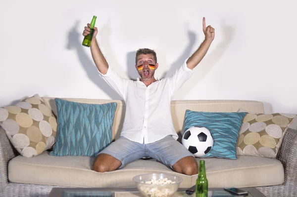 Joven hombre atractivo partidario del fútbol con bandera de Alemania pintó la cara feliz y emocionado viendo partido de copa en la televisión celebrando la victoria gol loco — Foto de Stock