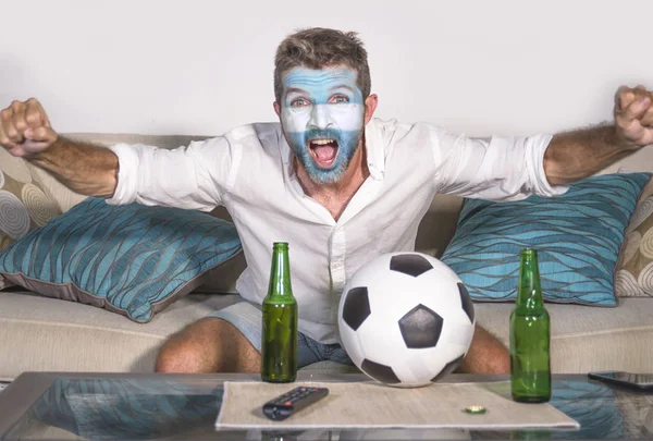 年轻有吸引力的人橄榄球支持者与阿根廷旗子绘了面孔愉快和激动观看杯子比赛在电视庆祝胜利目标疯狂 — 图库照片