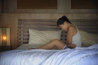 genç güzel ve oldukça Asya Çinli kadın hasta ve hasta göbek ve karın kramp ve Hayız adet ağrısı acı duygu yatakta yatarken