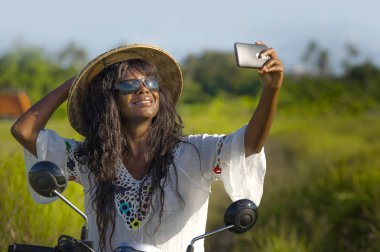 Asya geleneksel şapka sürme motosiklet selfie fotoğraf gülümseyen hareket eden telefon ile mutlu çekici genç çekici siyah afro Amerikalı turist kadın