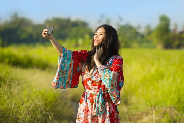 Mladá, krásná a šťastná asijské čínských turistů ženě na její 20s s barevné šaty s selfie pic fotoaparátem mobilního telefonu na tropické oblasti — Stock fotografie