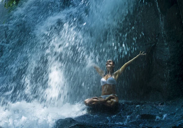 Attraktive Frau sitzt am Felsen in Yoga-Pose für spirituelle Entspannung Gelassenheit und Meditation an atemberaubend schönen Wasserfall und Regenwald in bali — Stockfoto
