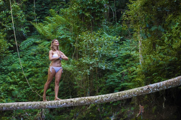 Schöne und attraktive Frau, die Yoga auf einem Baum praktiziert — Stockfoto