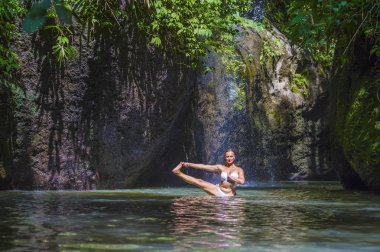 çekici ve formda turist Kafkas kadın pratik yoga egzersiz poz şaşırtıcı tropikal egzotik şelale lagün ile yeşil turkuaz su renk
