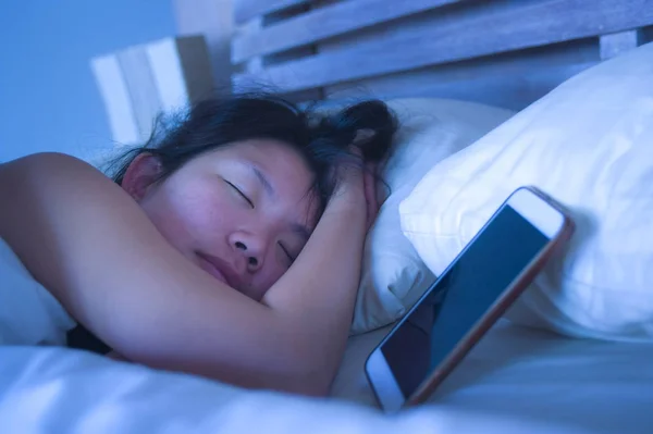 Close-up van portret van de jonge zoete en mooie Aziatische Chinese vrouw 20s of 30s slapen in bed naast haar mobiele telefoon in internet-sociale media-verslaving — Stockfoto