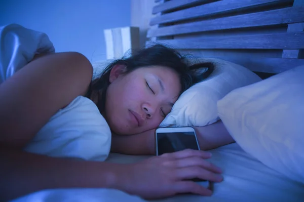 Portré, fiatal és gyönyörű ázsiai kínai nő 20s és 30s alszik az ágyban, a mozgatható telefon-ban internet szociális média-függőség mellett közelről — Stock Fotó
