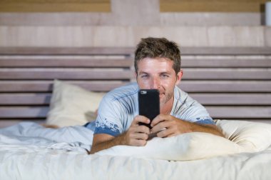 Internet cep telefonuyla sosyal medya ve hücresel iletişim bağımlılığı gönderen metin gülümseyen yatakta yatan genç çekici ve mutlu adam 