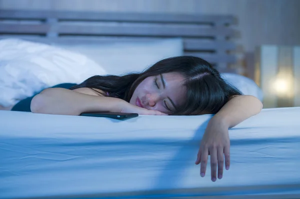 Крупним планом портрет молодого солодкі і красиві азіатські Китайська жінка, що 20 років або 30s, спати в ліжку поруч зі свого мобільного телефону в соціальних медіа Інтернет-залежність — стокове фото