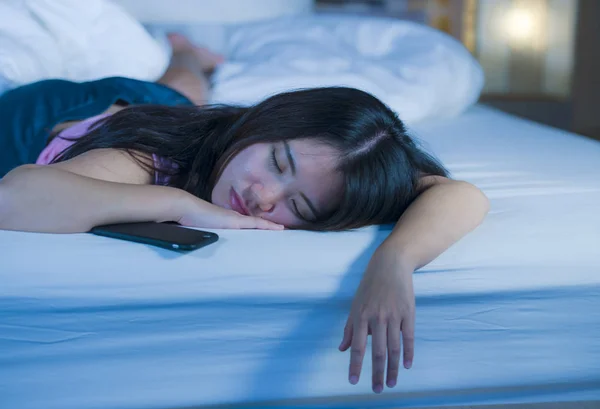 Potret wanita muda Cina Asia yang manis dan cantik 20-an atau 30-an tidur di tempat tidur di samping ponselnya dalam kecanduan media sosial internet — Stok Foto