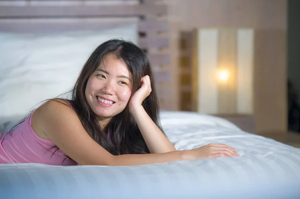 美しく、甘いアジア中国女遊び心と陽気な笑みを浮かべて彼女の居心地の良いベッドルームにベッドでリラックスして幸せは快適な横になっています。 — ストック写真