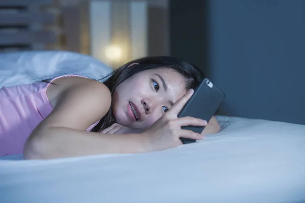 Молодые сладкие и красивые азиатские китайские 20-х или 30-х годов женщина улыбается счастливый лежа на кровати с помощью интернет-знакомств мобильного телефона или отправки текста на ночь — стоковое фото