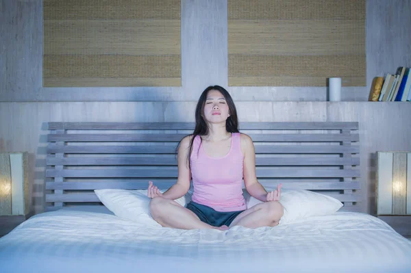 Young pretty Asian Chinese woman 20s or 30s relaxing at home bedroom sitting on bed in lotus yoga position in meditation and relaxation exercise — Stock Photo, Image