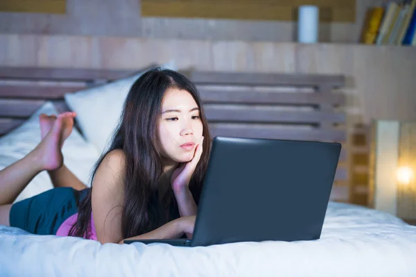 Młode atrakcyjne i piękne 20s azjatycki chiński kobieta leżąc na łóżku w nocy za pomocą Internetu w laptopa, oglądanie filmu linii na zrelaksowany — Zdjęcie stockowe