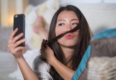 genç güzel ve mutlu Asyalı Çinli kadın evde kanepe yalan Internet üzerinden app içinde hareket eden telefon selfie portre alarak dating kanepe