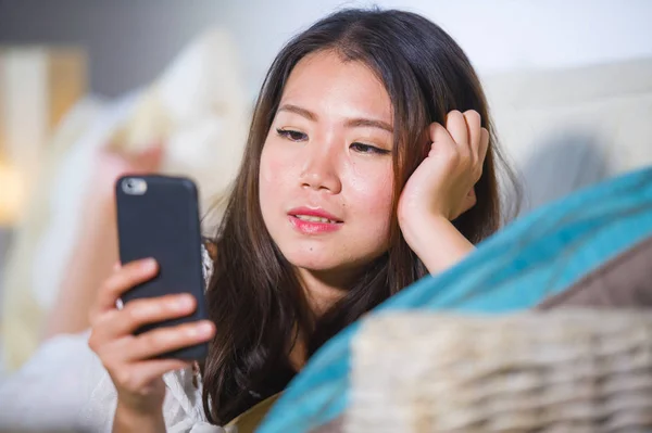 Jeune belle et heureuse asiatique chinois femme sur son 20s ou 30s couché sur canapé salon en utilisant Internet téléphone mobile à la recherche magnifique — Photo