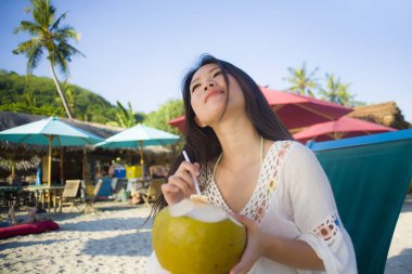 genç güzel ve mutlu Asya Kore dili veya Çince kadın 20'li yaşlarda içme rahat Hindistan cevizi suyu tropik cennet plaj resort yaz tatilleri 