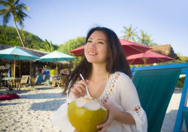 genç güzel ve mutlu Asya Kore dili veya Çince kadın 20'li yaşlarda içme rahat Hindistan cevizi suyu tropik cennet plaj resort yaz tatilleri 