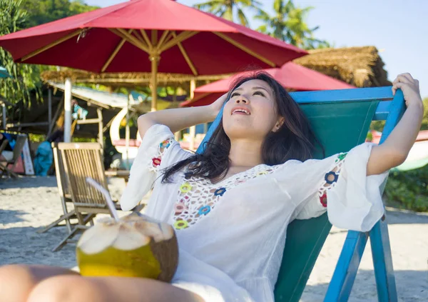 Молодая красивая и счастливая азиатская кореянка или китаянка 20 лет пьет расслабляющий кокосовый сок на тропическом райском курорте во время летних каникул — стоковое фото