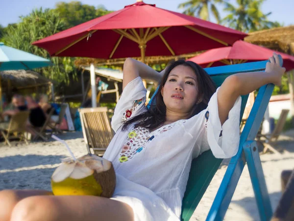 Молодая красивая и счастливая азиатская кореянка или китаянка 20 лет пьет расслабляющий кокосовый сок на тропическом райском курорте во время летних каникул — стоковое фото