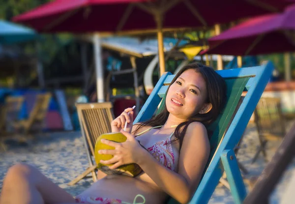 Young beautiful and happy Asian Korean or Chinese woman 20s drinking relaxed coconut juice on tropical paradise beach resort in summer holidays — Stock Photo, Image