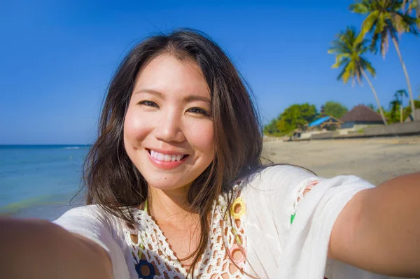Автопортрет великолепной красивой и счастливой азиатской корейской или китайской женщины 20 лет, делающей селфи с камерой мобильного телефона на экзотическом тропическом пляже — стоковое фото