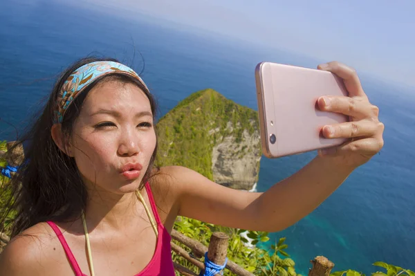 Jovem bonita e feliz asiático coreano turista mulher sorrindo tomando selfie retrato com celular na praia mar penhasco paisagem fundo — Fotografia de Stock