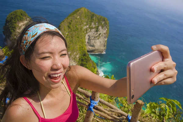 Joven hermosa y feliz asiático coreano turista mujer sonriendo tomando selfie retrato con teléfono móvil en playa acantilado paisaje fondo — Foto de Stock