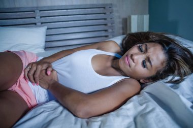 mide bel tutan yatakta yatan genç Asya Tayland veya Malay kadın