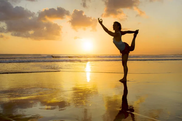 Genç zinde ve plaj gün batımı yoga pratik egzersiz daimi deniz önünde ıslak güneş üzerinde meditasyon çekici spor kadın silüeti — Stok fotoğraf