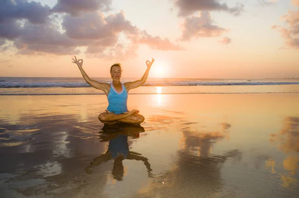 Mujer joven en forma y atractivo deporte en playa puesta del sol yoga práctica entrenamiento sentado en sol húmedo en frente del mar en la meditación y el ejercicio de relajación — Foto de Stock