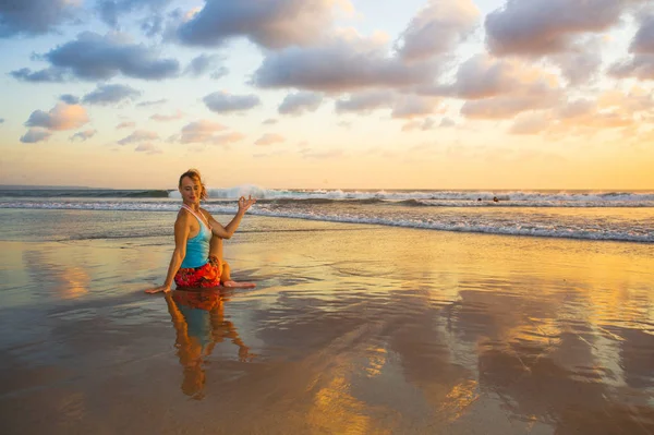 Mujer joven en forma y atractivo deporte en playa puesta del sol yoga práctica entrenamiento sentado en sol húmedo en frente del mar en la meditación y el ejercicio de relajación — Foto de Stock