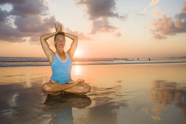 Mujer joven en forma y atractivo deporte en playa puesta del sol yoga práctica entrenamiento sentado en sol húmedo en frente del mar en la meditación y el ejercicio de relajación — Foto de Stock