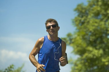 genç çekici runner adam asfalt yol egzersiz güneşli bir yaz sabahı çevrili ağaçlar ve bitki örtüsü tarafından çalışan eğitim spor