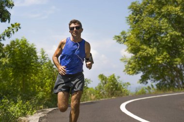 genç çekici runner adam asfalt yol egzersiz güneşli bir yaz sabahı çevrili ağaçlar ve bitki örtüsü tarafından çalışan eğitim spor