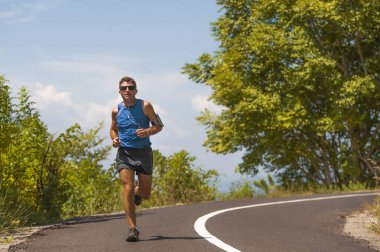 genç çekici runner adam asfalt yol egzersiz güneşli bir yaz sabahı çevrili ağaçlar ve bitki örtüsü tarafından çalışan eğitim spor