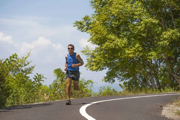 Молодий привабливий спорт бігун тренування в асфальтній дорозі тренування сонячного літнього ранку в оточенні дерев і рослинності — стокове фото