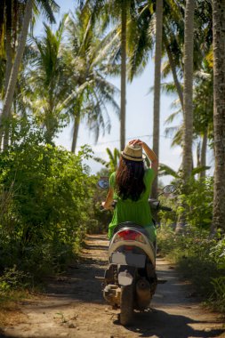 Genç mutlu turist kadın mavi gökyüzü ve palm ile tropik cenneti ormanda scooter motosiklet sürme şapka ile keşfetmek seyahat hedef ağaçlar