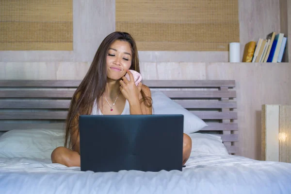 Молодая привлекательная и счастливая азиатская латиноамериканская этническая смешанная женщина в постели с помощью ноутбука компьютер изучения или наслаждаясь Интернетом расслабленной питьевой кофе — стоковое фото