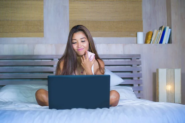 Jonge aantrekkelijke en gelukkig Aziatische hispanic etniciteit gemengd vrouw in bed met laptopcomputer studeren of genieten van de ontspannen koffie drinken internet — Stockfoto