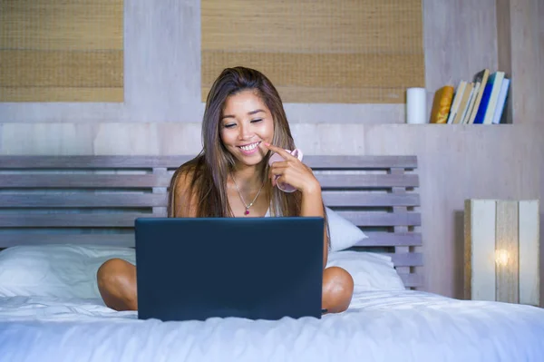 Jonge aantrekkelijke en gelukkig Aziatische hispanic etniciteit gemengd vrouw in bed met laptopcomputer studeren of genieten van de ontspannen koffie drinken internet — Stockfoto