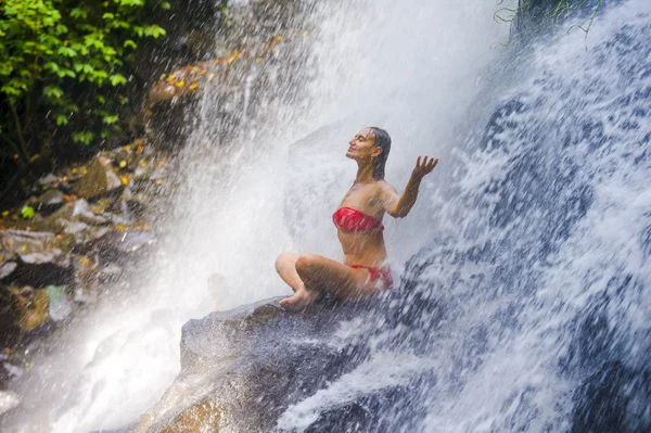 Joven atractiva y feliz mujer de los años 30 con cuerpo en forma practicando yoga mojado bajo la corriente de cascada del paraíso tropical en meditación y relajación — Foto de Stock