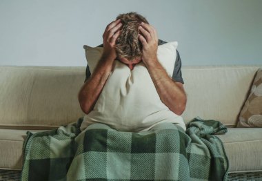 Genç üzgün ve umutsuz adam evde kapsayan yüz eller ve acı depresyon ağlıyor yastık ile kanepe oturma kanepe oturma ve duygu sefil üzüntü ve yaşam tarzı kavram stres