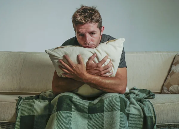 Jeune homme triste et désespéré à la maison assis sur le canapé tenant l'oreiller souffrant de dépression et de stress inquiet de problème se sentant misérable — Photo