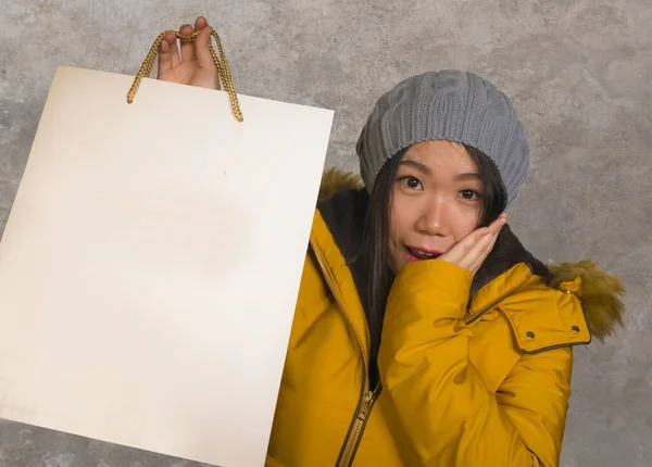Joven hermosa y feliz mujer coreana asiática en fresco sombrero de invierno celebración bolsa de compras emocionada compra regalo de Navidad sonriente alegre en concepto de moda y belleza — Foto de Stock