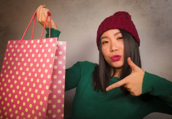 Młody piękny i szczęśliwy Azji koreański kobieta w chłodny zimowy kapelusz gospodarstwa torba zakupy podekscytowany zakup świąteczny prezent uśmiechnięty w moda piękno koncepcja odizolowany — Zdjęcie stockowe