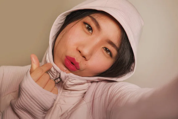 若い美しく幸せなアジア系韓国人女子高生が自撮りポートレート写真を撮影し、 SNSアプリを使って遊び心のある笑顔ジェスチャー甘いヒップスタースタイルのフード — ストック写真