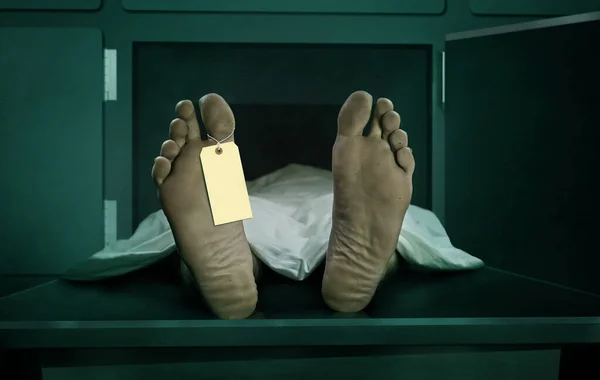 Männliche menschliche Leiche liegt tot in Leichenschaukapsel mit leerem Identifikationsetikett. Nahaufnahme Fuß des Mannes Kadaver mit Laken bedeckt mit Identitätsmarke auf Zehe in Todeskonzept — Stockfoto