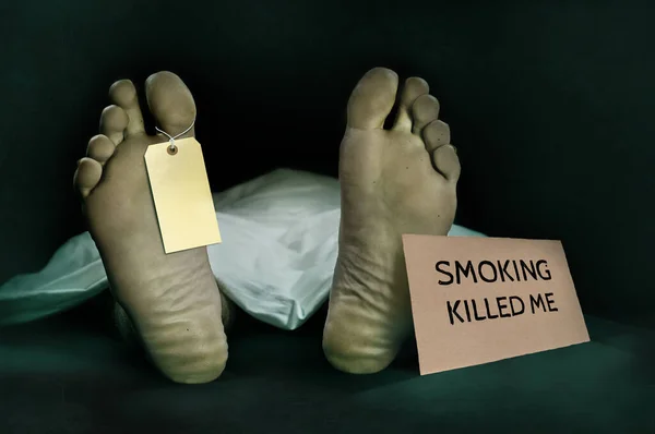 Campagne anti tabac. cadavre à la morgue avec une étiquette d'identité vierge recouverte d'une feuille et fumer tuer panneau d'avertissement dans le cancer mort et danger de dépendance aux cigarettes — Photo